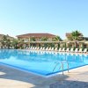 Grande piscina con sdraio e ombrelloni, edificio sullo sfondo.